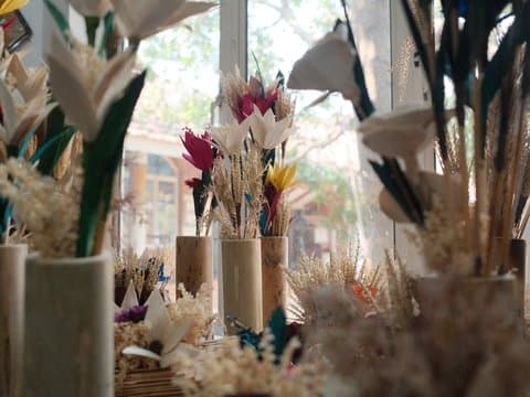 A collection of dried flowers in vases, with sunlight filtering through a window.