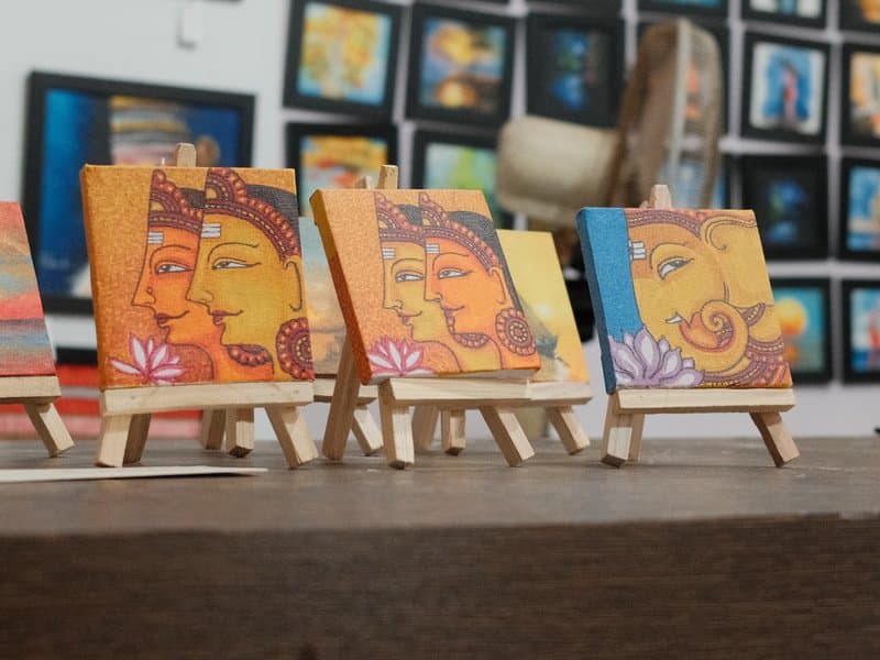 Small paintings of faces displayed on easels in an art gallery.