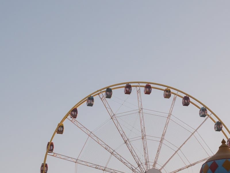 A close-up view of a ferris wheel against a clear sky, showcasing colorful cabins.
