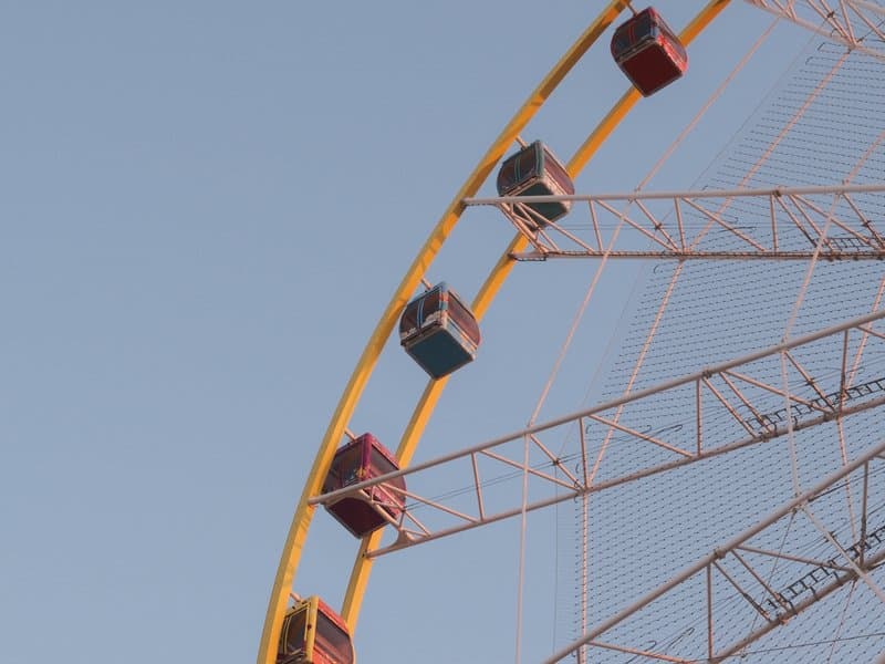 Close-up of a colorful ferris wheel against a clear blue sky.