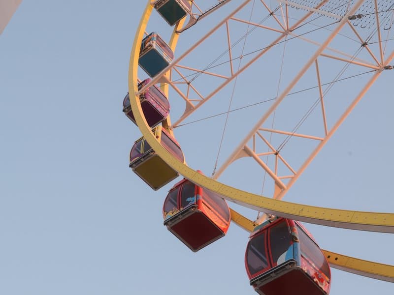 Close-up of a colorful ferris wheel against a clear sky.