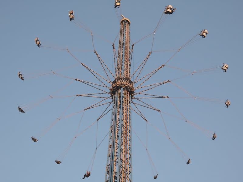 A tall amusement park ride with swinging seats against a clear blue sky.