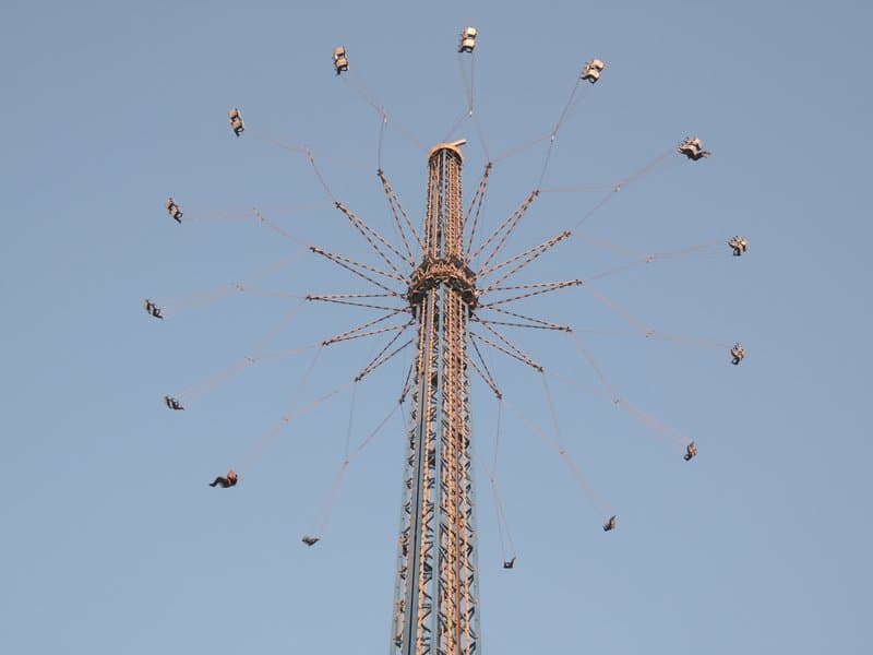 A tall amusement park ride with swinging seats against a clear blue sky.