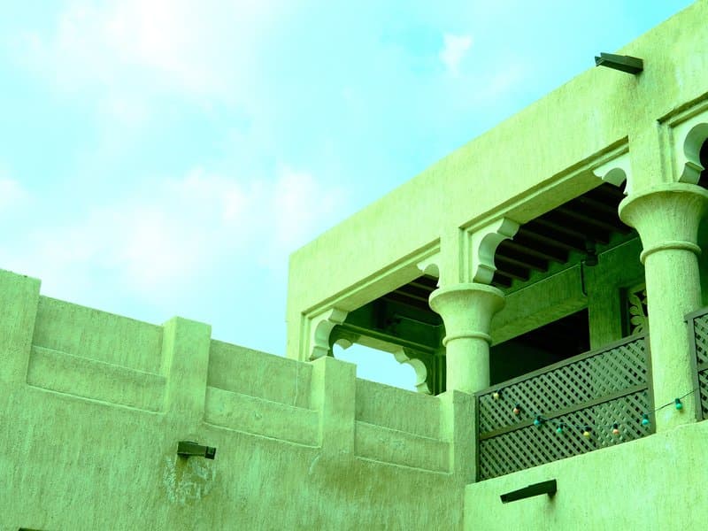 A green-tinted architectural structure with arches and columns against a cloudy sky.