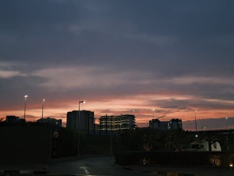 A sunset scene with a colorful sky over urban buildings and streetlights.