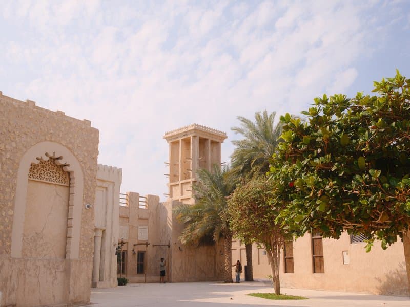 Historic architecture with a tower surrounded by palm trees under a cloudy sky.