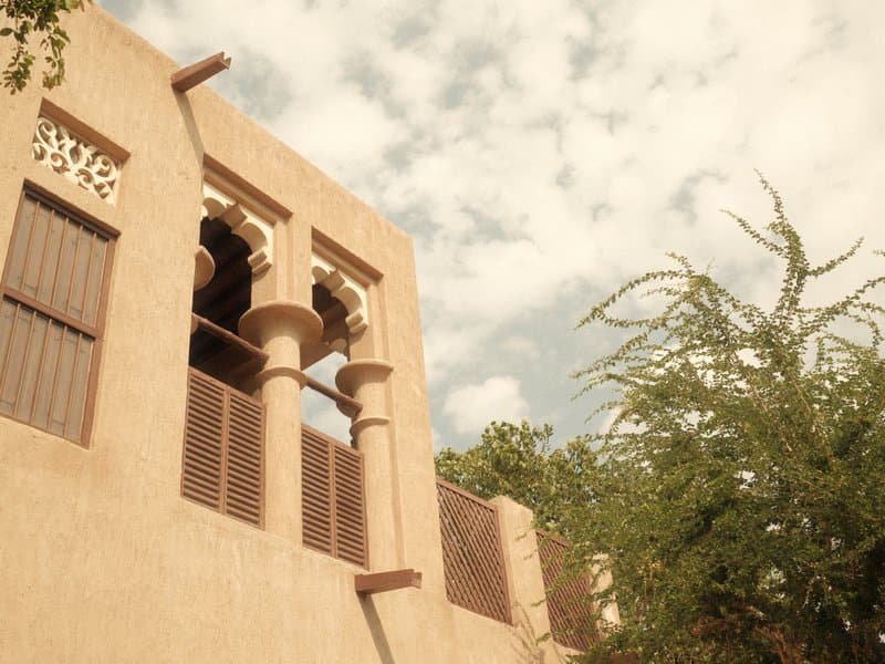 A historic building with arched windows and wooden shutters against a cloudy sky.