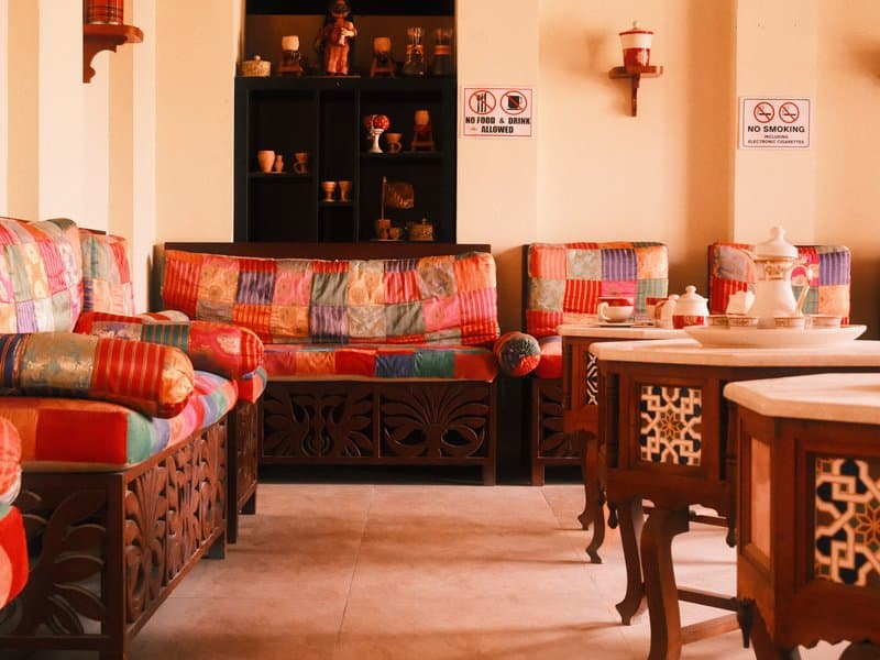 Colorful seating area with patterned cushions and wooden furniture in a cozy indoor setting.