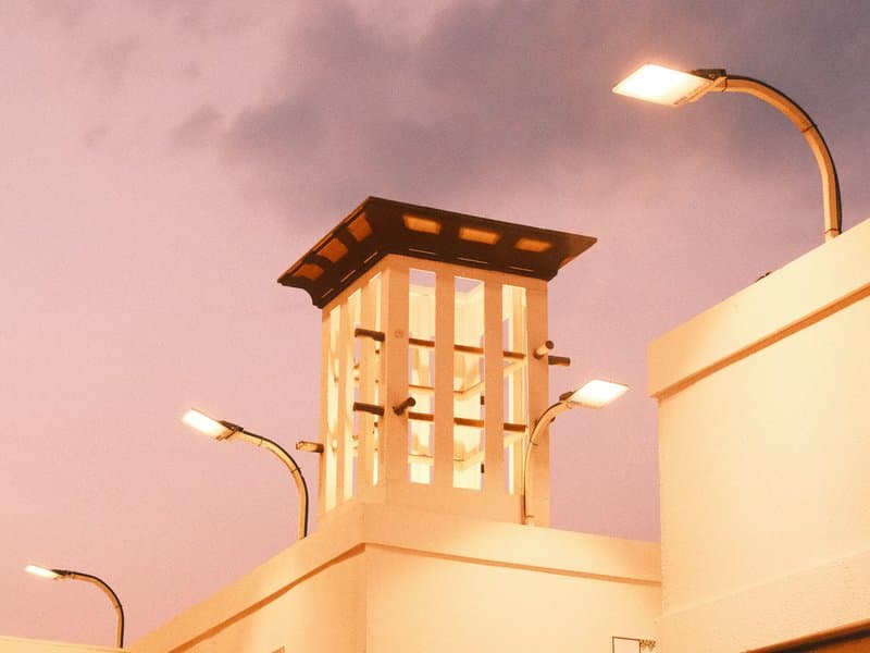 A decorative tower with lights against a pastel pink sky at dusk.