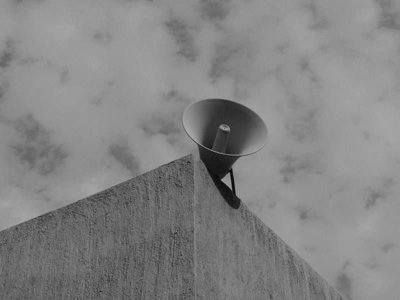 A large megaphone mounted on a concrete building under a cloudy sky.