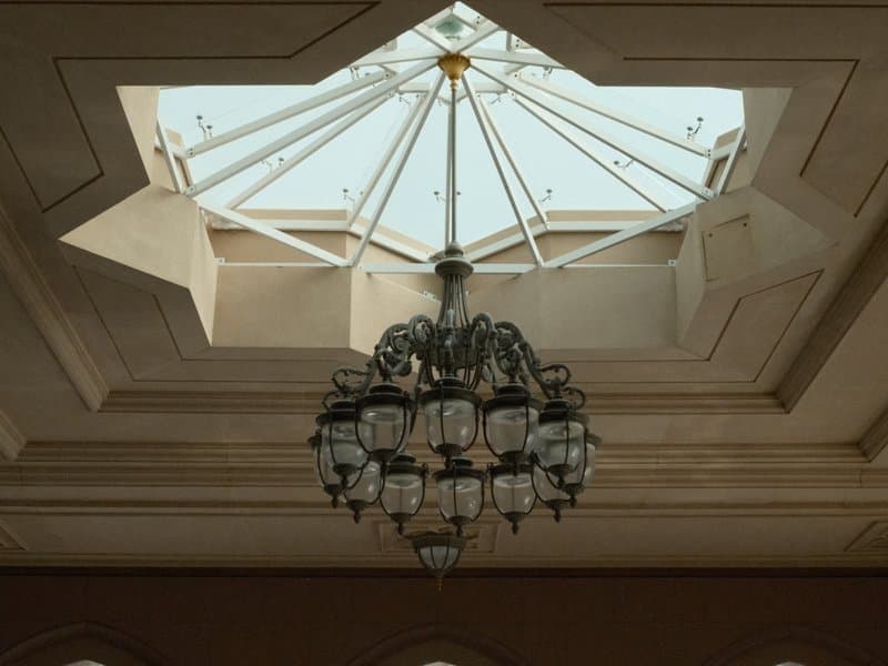 A decorative chandelier hanging from a star-shaped skylight in a ceiling.