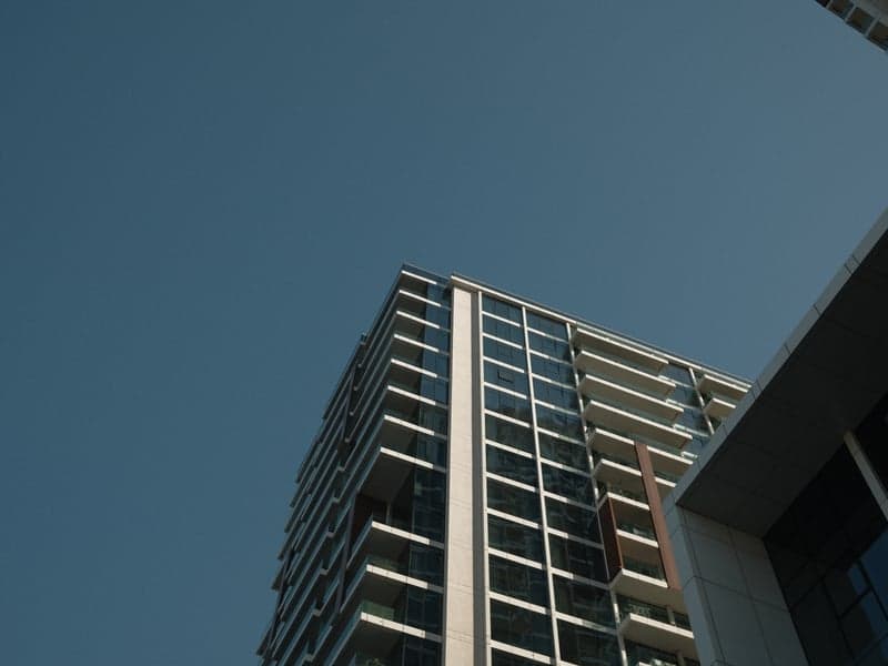 A tall modern building reaching towards a clear blue sky, showcasing architectural lines and glass.