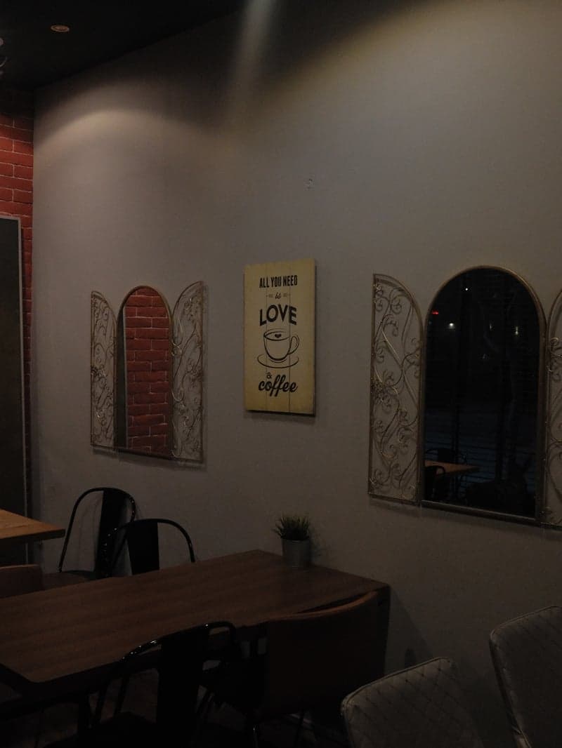 Interior of a cozy café with a wall featuring decorative windows and a love-themed sign.