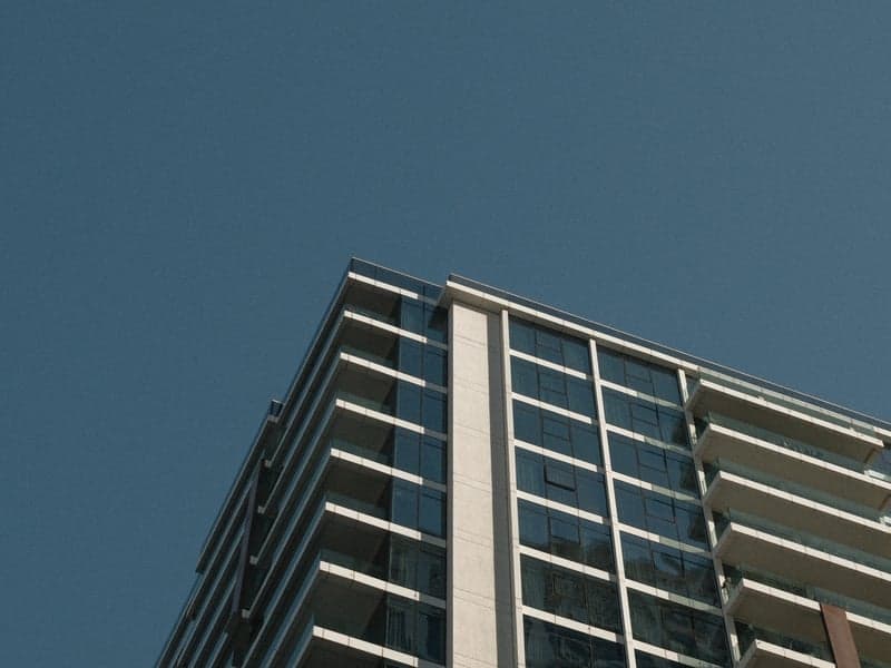 A modern building with glass windows against a clear blue sky, showcasing architectural design.
