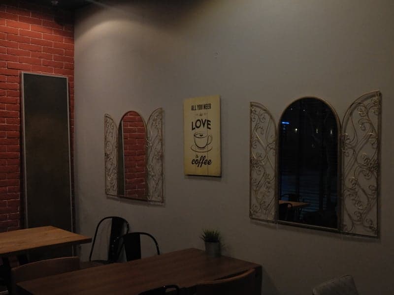 Interior of a cozy cafe with decorative windows and a love-themed painting on the wall.