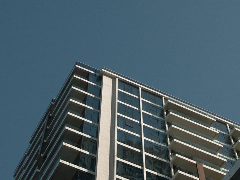A modern glass building against a clear blue sky, showcasing architectural lines and reflections.