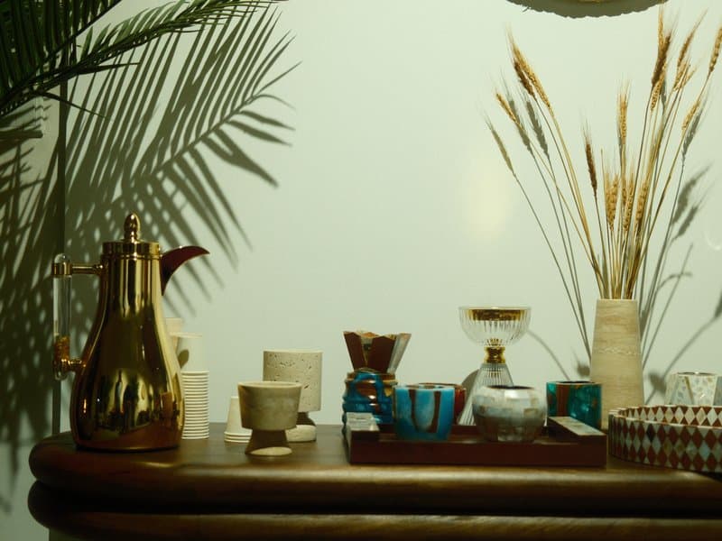 A stylish coffee setup on a wooden table featuring various cups, a coffee maker, and decorative plants.