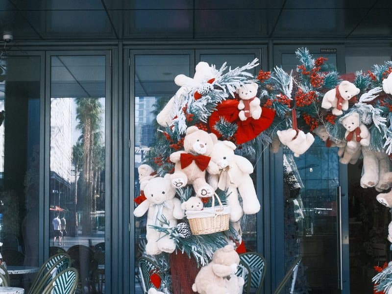 A festive display of teddy bears and decorations on a storefront entrance.