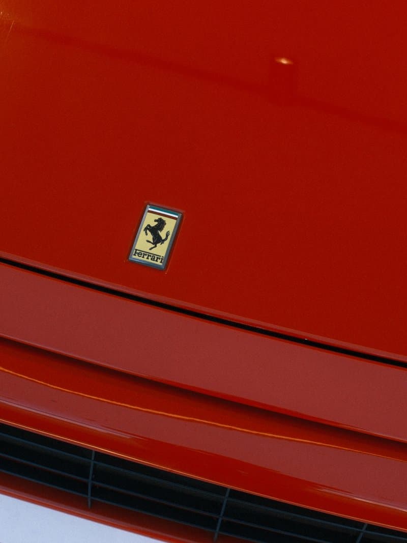 Close-up of a red Ferrari car hood featuring the iconic prancing horse emblem.