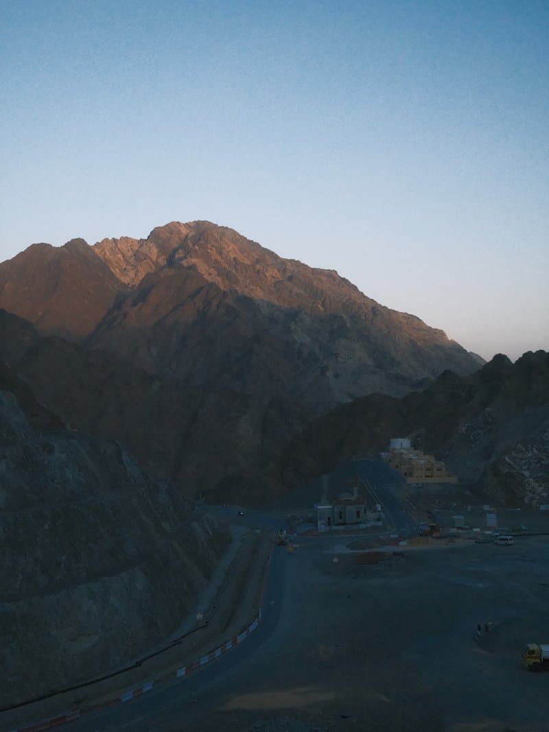 A mountain landscape at dusk with soft light illuminating the peaks and shadows in the valleys.